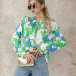 Oversizowa bluzka w biało niebieskie kwiaty na zielonym tle.