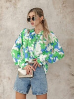 Oversizowa bluzka w biało niebieskie kwiaty na zielonym tle.