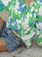 Wiskozowa bluzka w biało - niebieskie kwiaty na zielonym tle.